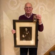 Nigel Carter with his grandfather Joe Brain's George Medal and a photograph of him