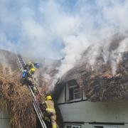 Dozens of firefighters tackle thatched roof fire