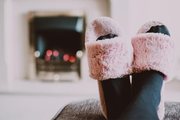 The Wiltshire Gazette and Herald: A person putting their feet up in fluffy slippers in front of the fire. Credit: Canva