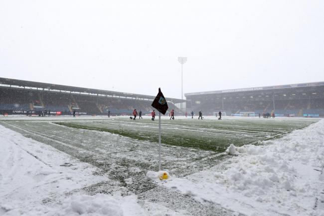 Snow is cleared from the pitch before the Premier League match at Turf Moor between Burnley and Tottenham