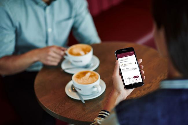 Two people drinking coffee using the Costa app. Credit: Costa Coffee