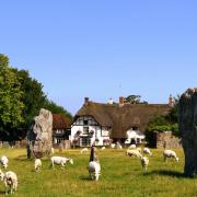 A sunlit view of large ancient standing stones and the village of Avebury north Wiltshire.