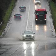 Vehicles driving through service water on a flooded part of the A37 near Bristo (Ben Birchall/PA)